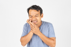 man experiencing a toothache with hand over mouth in pain
