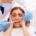 woman afraid of dentist holding her face as dentist has tools next to it