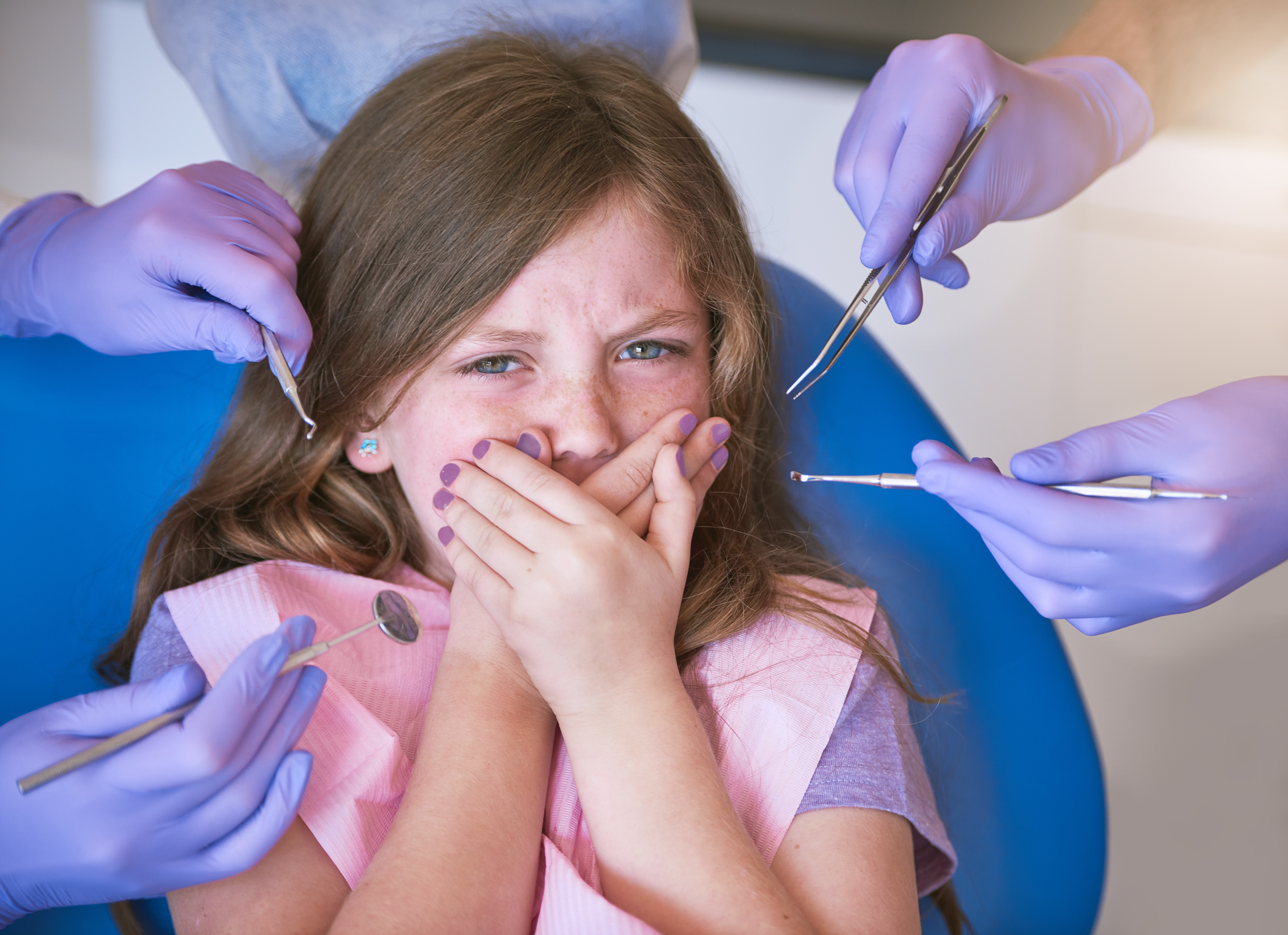 little girl scared of the dentist as the dental tools are being placed around her head